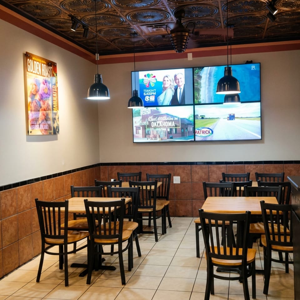 Empty casual restaurant dining area with wooden tables, black chairs, pendant lights, promotional posters, and wall-mounted televisions.